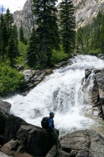 Man hiking by mountain waterfall