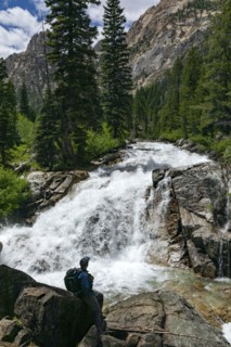 Man hiking by mountain waterfall