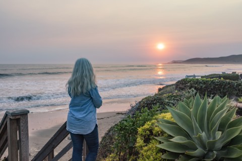 Woman watching sunset from bluff above beach