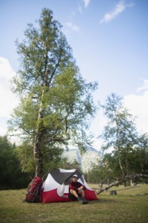 Hiker sitting by tent in mountains