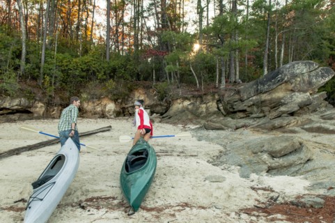 Couple pulling kayaks on rocks