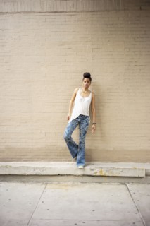 Serious African American woman standing on ledge at brick wall