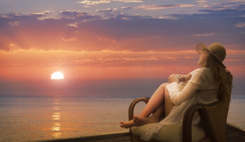 Caucasian woman admiring sunset on beach