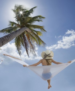 Caucasian woman sitting in hammock under palm tree