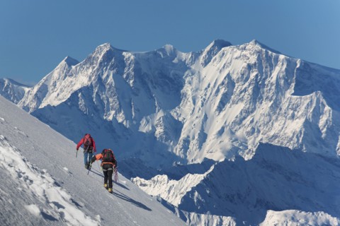 Caucasian hikers climbing snowy mountain