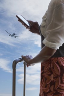 Chinese traveler using cell phone under airplane in blue sky