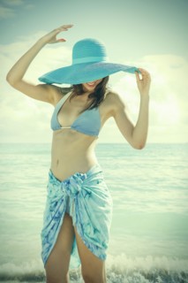 Caucasian woman wearing bikini and sun hat on beach
