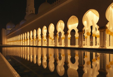 Illuminated colonnade reflecting in still pool