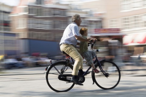 Blurred view of father and son bicycling on city street