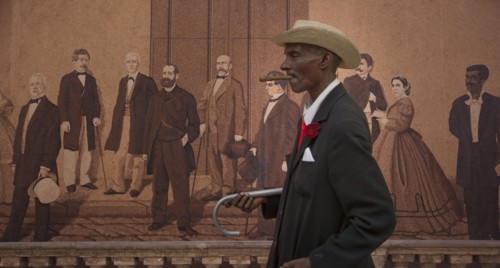 Hispanic man walking past mural