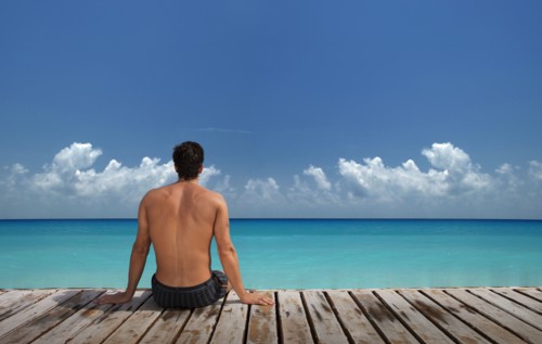Caucasian man sitting on wooden dock at ocean