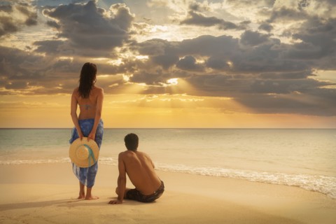 Caucasian couple admiring sunset on beach