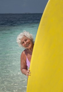 Older Caucasian woman holding surfboard on beach