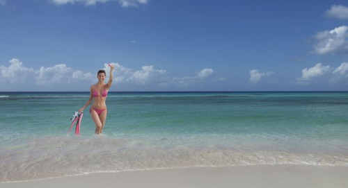 Caucasian woman wading on beach with flippers and snorkel