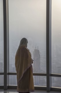 Asian woman at window admiring Dubai cityscape