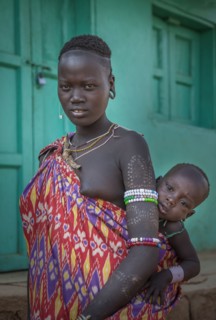 Black woman carrying daughter in sling