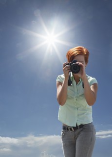 Caucasian woman photographing under blue sky