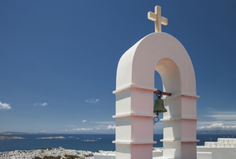 Bell arch and Mykonos cityscape under blue sky
