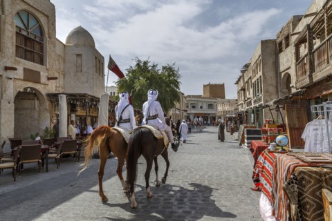Men riding horses on Doha street