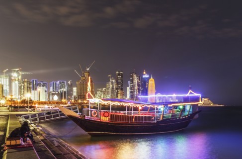 Illuminated boat docked in Doha harbor