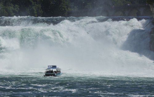 Boat floating near dramatic waterfall