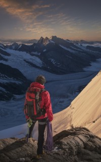 Caucasian man admiring mountain range holding climbing rope
