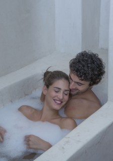 Smiling Caucasian couple relaxing in bathtub