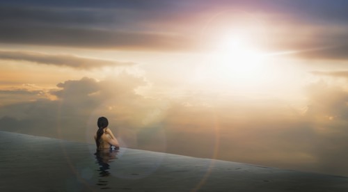 Chinese woman in infinity pool admiring sunset