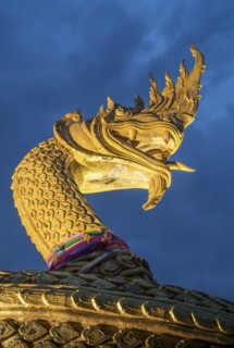 Ornate golden snake statue under cloudy sky