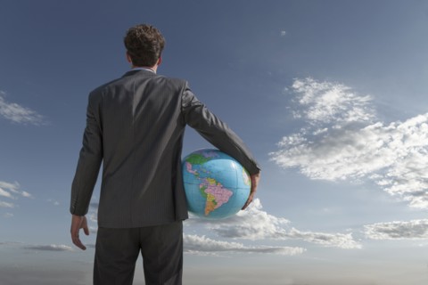 Caucasian businessman holding globe in sky
