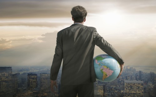 Caucasian businessman holding globe overlooking cityscape