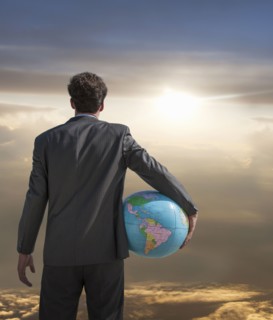 Caucasian businessman holding globe admiring sunset sky