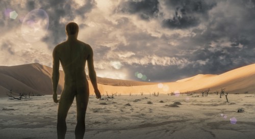 Naked man standing in desert