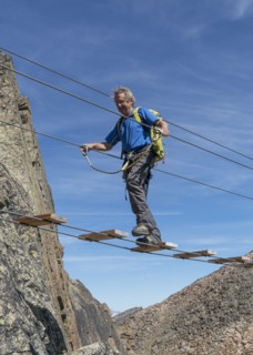 Caucasian man crossing rope bridge on mountain