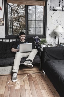 Mixed race man sitting on sofa with laptop