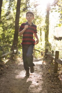 Caucasian boy running on path in forest