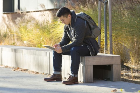 Mixed race college student using digital tablet on campus