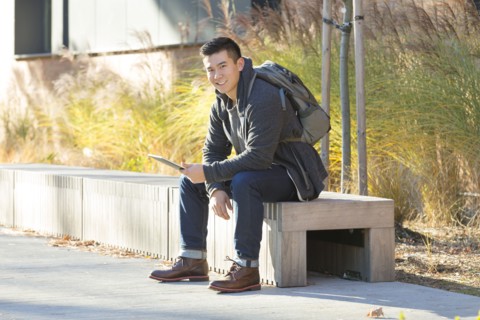 Mixed race college student using digital tablet on campus