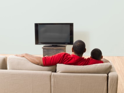 Father and son watching television in living room