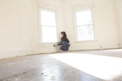 Mixed race woman cleaning wall in new home
