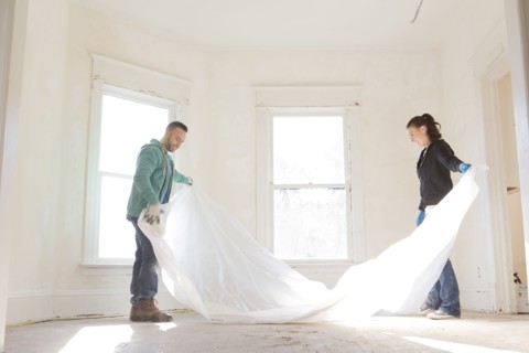 Mixed race couple spreading tarp in new home