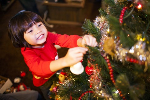 Mixed race girl decorating Christmas tree