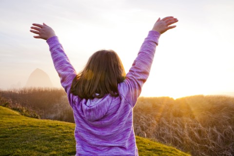 Caucasian girl cheering on rural cliffs