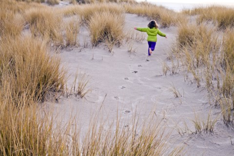 Caucasian girl running on sand dunes
