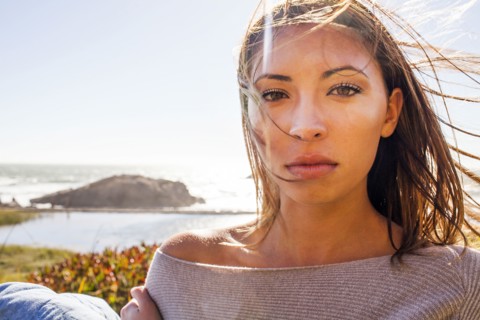 Mixed race woman's hair blowing in wind on coastal hillside