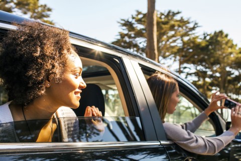 Women taking cell phone picture together in car