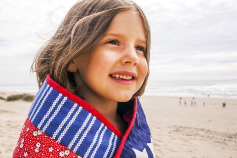 Caucasian girl wrapped in blanket on beach