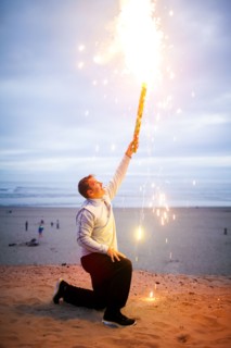 Caucasian man holding fireworks on beach
