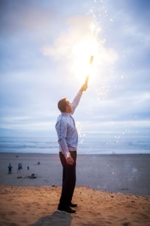 Caucasian man holding fireworks on beach