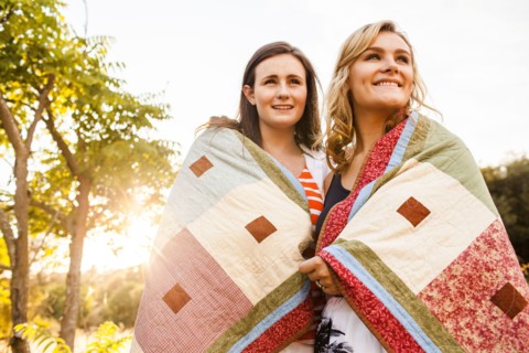 Caucasian teenage girls wrapped in blanket outdoors